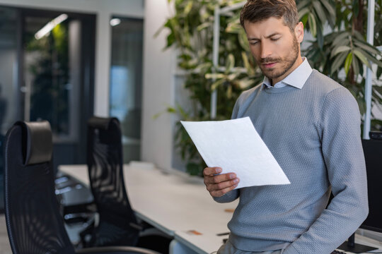 Smiling handsome businessman manager standing in office with documents