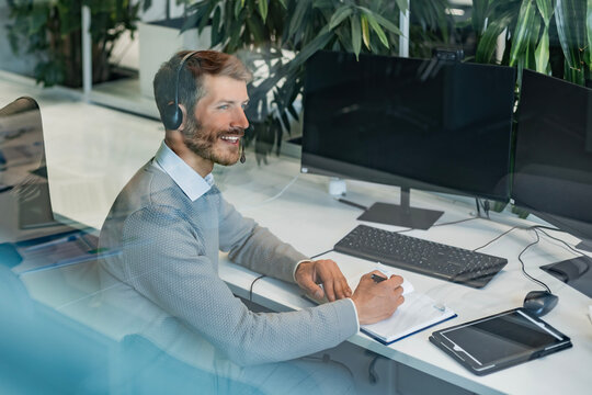 Happy call center agent wearing headset talking to client working in customer support office
