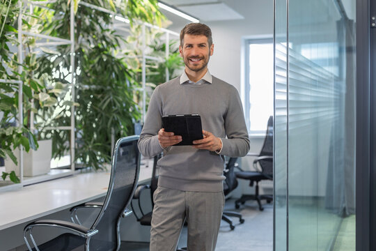 Modern business man in formalwear using digital tablet while standing in the office
