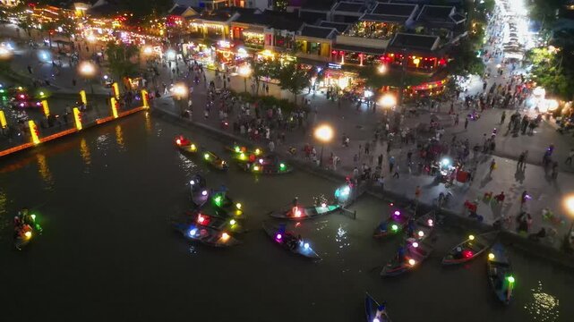 Aerial view of Hoi An ancient town with night market, cafes, boats and bridge.