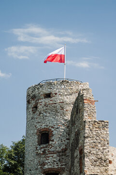 Round stone castle tower with Polish flag under blue sky real photography