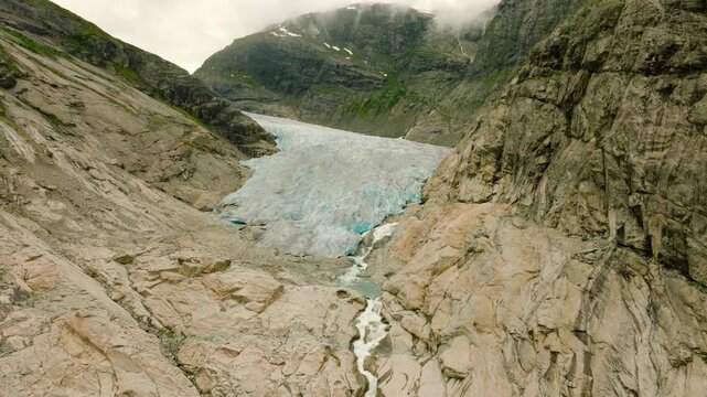 Aerial drone footage of the Nigardsbreen glacier, one of the glacier arms of the Jostedalsbreen ice cap in Norway. Various views show the blue-white glacier ice, crevasses, rocky surroundings and melt