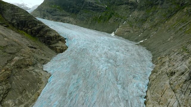 Aerial drone footage of the Nigardsbreen glacier, one of the glacier arms of the Jostedalsbreen ice cap in Norway. Various views show the blue-white glacier ice, crevasses, rocky surroundings and melt