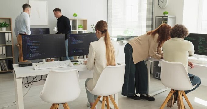 Developers team programmers coders teamwork office collaboration. Coworkers pair at screens, coding modules and fixes in an office while doing review for quality. Clear concept of modern teamwork.