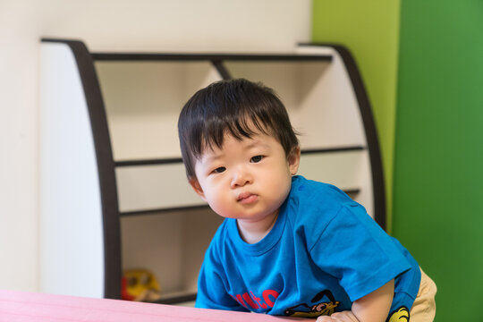 キッズルームのピンクのソフトブロックにもたれている日本人の男の赤ちゃん