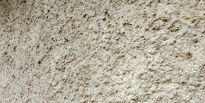 Rough gray concrete wall texture with surface full of small holes.