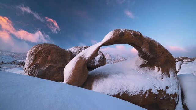 A rare view of snow over the famous Mobius Arch during the mornings first light after a big snowfall. This hyperlapse has moody clouds and golden light in Alabama Hills, ca.