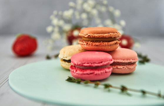 French colorful macaroons. Colorful pastel macaroons on a light background with fresh strawberries. Concept soft focus.