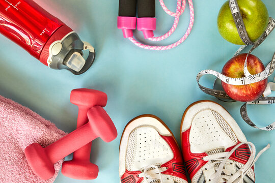 Attributes of a healthy lifestyle. Fruits, dumbbells, water bottle, rope, sneakers and meter on a blue background. Calorie counting. Diet plan. View from above. Sports and healthy regime. Copy space.