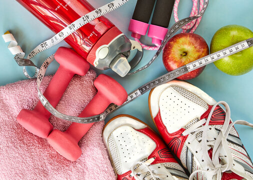 Attributes of a healthy lifestyle. Fruits, dumbbells, water bottle, rope, sneakers and meter on a blue background. Calorie counting. Diet plan. View from above. Sports and healthy regime.