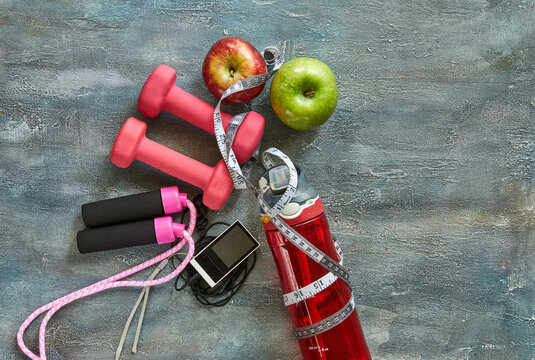 Attributes of a healthy lifestyle. Fruits, dumbbells, a bottle of water, rope, meter, player on a blue background with stains. Diet plan. View from above. Sport and healthy mode. Copy space.