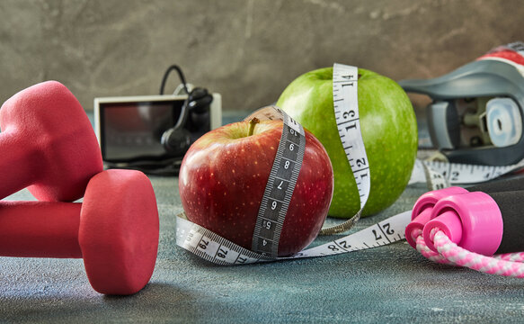 Attributes of a healthy lifestyle. Fruits, dumbbells, a bottle of water, rope, meter, player on a blue background with stains. Diet plan. Side view. Sport and healthy mode.