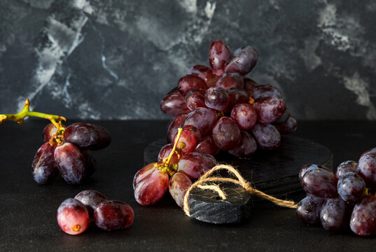 Grapes on a dark background and a black wooden stand.