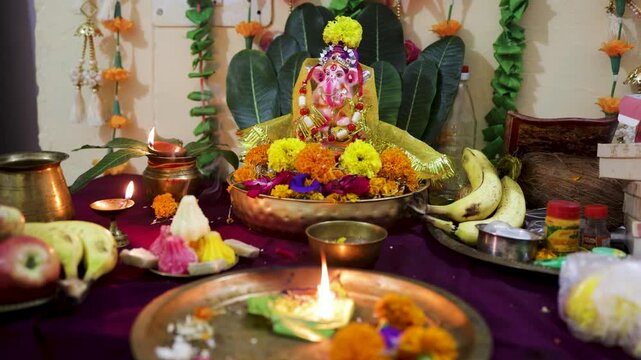 Traditional Ganesh Puja Setup Featuring Idol Diyas Prasad And Sacred Floral Decorations
