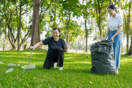 Asian Women Volunteers Collecting Plastic Bottle Garbage into Trash Bag in Green Park for Environmental Protection and Recycling Concept