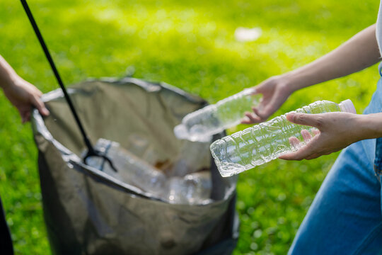Asian Women Volunteers Collecting Plastic Bottle Garbage into Trash Bag in Green Park for Environmental Protection and Recycling Concept