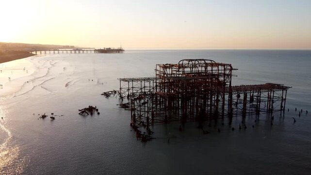 Drone shot panning backwards from the ruins of the West Pier as the sea and cityscape is revealed under the sunrise over the city