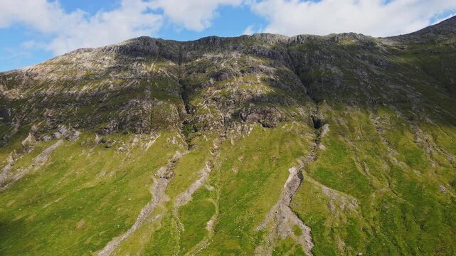Beautiful aerial view of a tall mountain ridge in the Scottish highlands in Glencoe, Scotland on a sunny, summer day