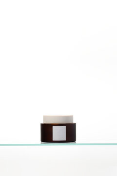 Cosmetic pot with blank label on bath shelf at clean white background. Minimal aesthetic ideal for skincare, wellness, and branding mockups.