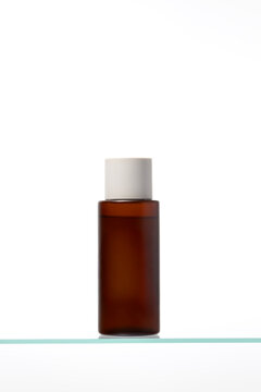Matte amber glass bottle with a neutral cap, centered on a glass surface. Excellent packaging mockup for facial toner, lotion, or essence in natural and apothecary-style cosmetic visuals