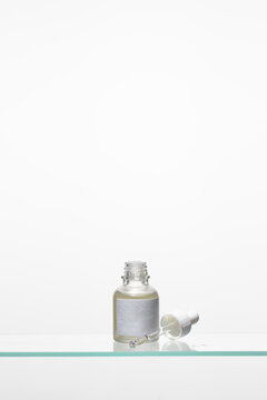 Abstract open dropper bottles with hydrating facial serum on the glass shelf for Japanese skin care, contemporary beauty