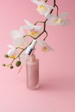 Open pink dropper bottle with orchid flowers, luxury skincare product visuals for advertising