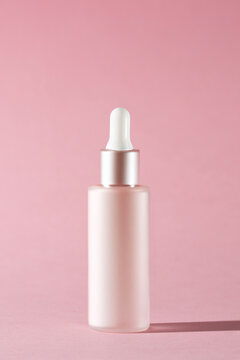 Pink dropper bottle on the pink background, luxury skincare product visuals for advertising