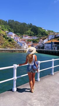 young woman with hat enjoying view over coastal fishing village in cudillero asturias spain