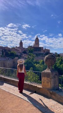young woman wearing hat looking at segovia cathedral skyline spain