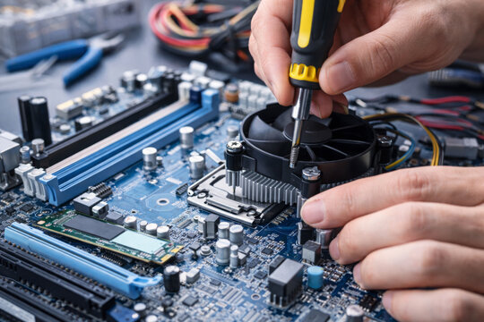 Motherboard assembly handled by technician using precise tools for computer repair and hardware engineering