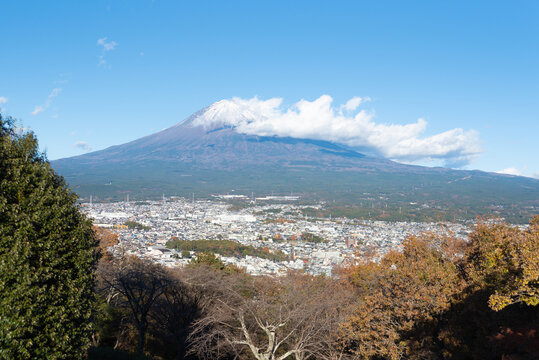 A scenic panoramic view of snow-capped Mount Fuji overlooking Fujinomiya city from Shirao Mountain Park (Shiraosan) in Japan, during a sunny December afternoon.