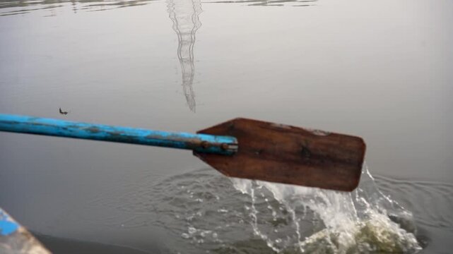 Wooden oar rowing a boat in calm river water with ripples and reflection in Delhi NCR India