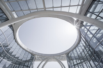 Fototapeta premium A modern architectural interior view of a circular skylight framed by glass and steel structures, showcasing sleek contemporary design.