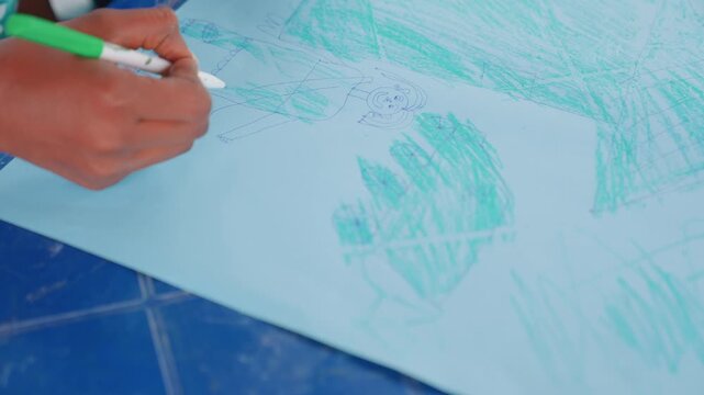 Child and mother drawing on floor with green crayon, closeup hand movements over blue tiles, playful dots and texture, tactile exploration, learning through creative play, informal workshop vibe