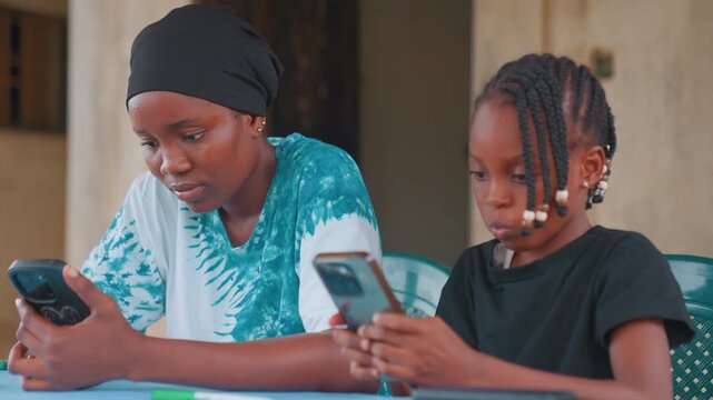 Mother monitors screen. Mother diligently reviews device settings to protect her child. Caretaker attentively supervises and regulates technology use to maintain safety and boundaries