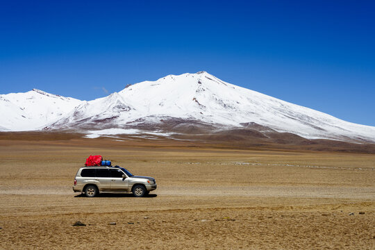 Four-wheel-drive parked below a snow-capped volcano on the altiplano, Sud L&iacute;pez, Potos&iacute;, Bolivia