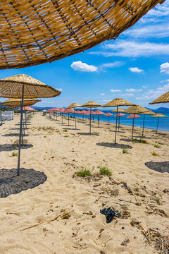 Sunny beach near cunda island on the aegean coast in turkey with straw umbrellas and turquoise sea. Travel, relaxation and summer vacation concept.