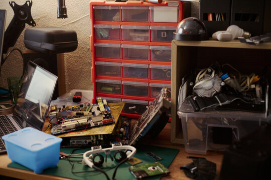 Computer hardware components lying on messy workshop desk with laptop and tools, representing electronics repair. Image suitable for IT support and hardware engineering services
