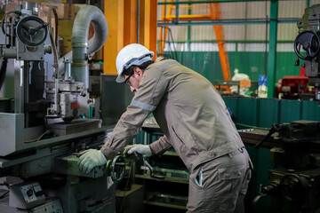 Fototapeta premium Factory worker machinist lathe workshop helmet glove metal equipment, focused male adult adjusting machine tool at industrial plant, protective workwear, precision manufacturing concept