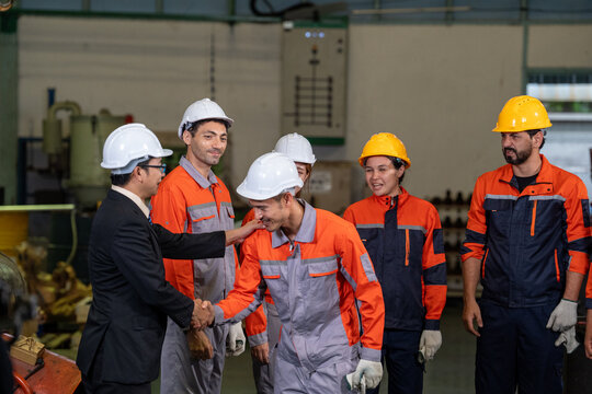 Engineer factory worker helmet team handshake safety uniform industrial meeting group inside production plant workshop