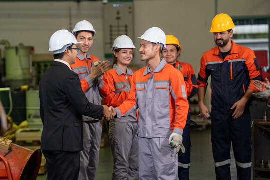 Engineer factory worker handshake safety helmet team industry uniform group greeting inside manufacturing plant