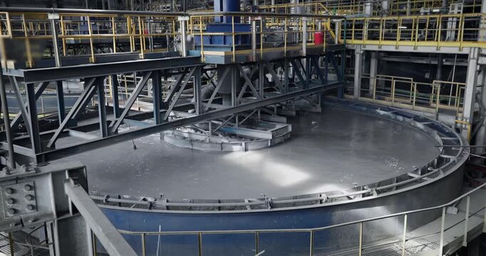 Flotation and processing circular clarifier tank for iron production from ore on mining factory. Closeup of fine pulp with bubbles, concentration industry plant..