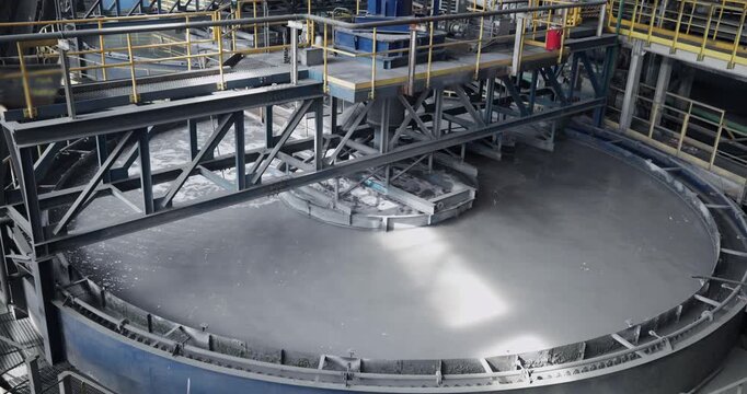 Flotation and processing circular clarifier tank for iron production from ore on mining factory. Closeup of fine pulp with bubbles, concentration industry plant.