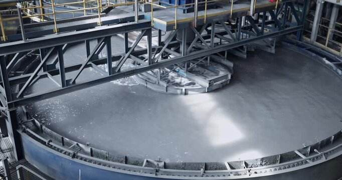 Flotation and processing circular clarifier tank for iron production from ore on mining factory. Closeup of fine pulp with bubbles, concentration industry plant.