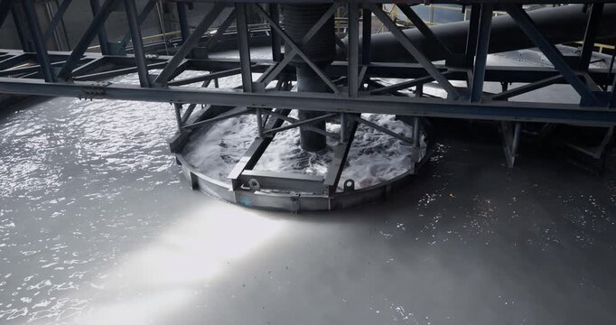 Closeup of fine pulp with bubbles, concentration industry plant. Flotation and processing circular clarifier tank for iron production from ore on mining factory.