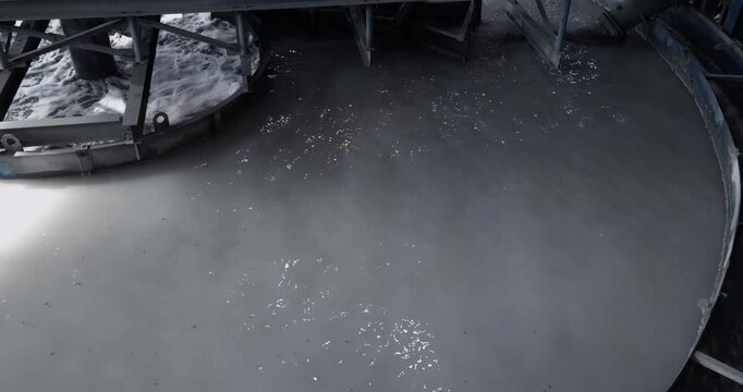 Closeup of fine pulp with bubbles, concentration industry plant. Flotation and processing circular clarifier tank for iron production from ore on mining factory.