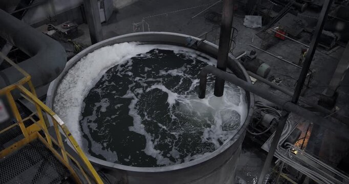 Closeup of fine pulp with bubbles, concentration industry plant, processing circular clarifier tank for iron production from ore, mining factory.