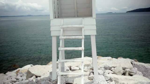 Tilt up reveal shot of the iconic white wooden tower at Khao Laem Ya Viewpoint, offering sweeping picturesque views of the ocean in Rayong Province, Thailand