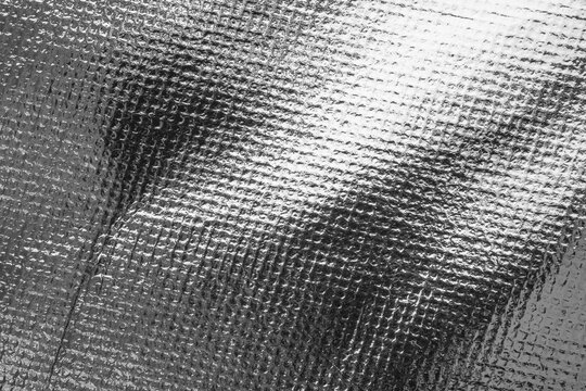 Silver foil texture background with embossed diamond pattern and shiny metallic surface reflection