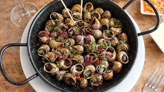 Casserole is filled with baked or boiled snails, and womens hands. Delicacy dish is made from grape snails and spices, recommended for use with red wine. 
